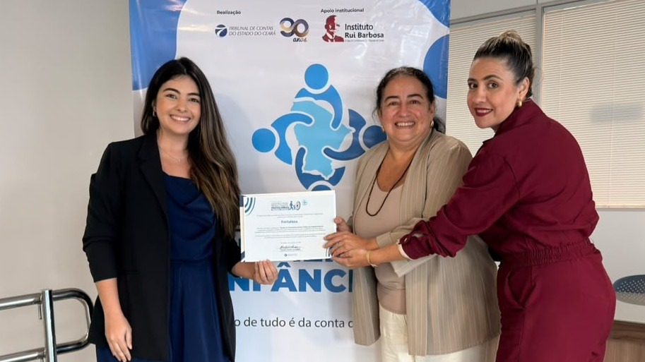 A coordenadora da primeira-infância posa com integrantes da Coordenadoria e o certificado do evento